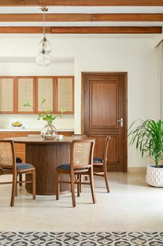 a dining room table with four chairs and a potted plant in the middle of it