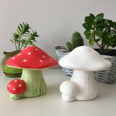 three small mushrooms sitting next to each other in front of a potted plant on a table