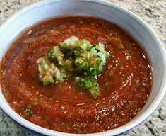 a bowl of soup with broccoli in it sitting on a marble counter top