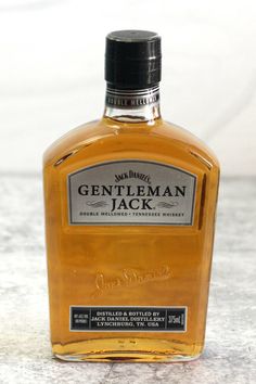 a bottle of gentleman jack whiskey sitting on top of a marble countertop in front of a white wall