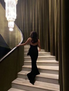 a woman is walking down the stairs in a black dress