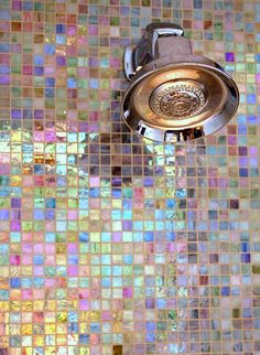 a faucet running from a shower head with colorful tiles on the wall behind it