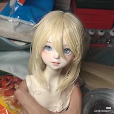 a doll with blonde hair and blue eyes sitting on a table next to pizza boxes