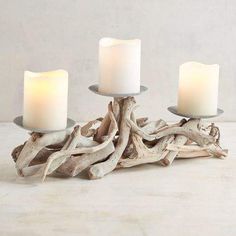 three candles sitting on top of driftwood pieces