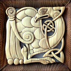 an intricate carved wooden plaque with a bird on it's head and two spirals in the middle