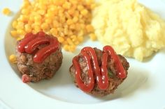 two meatballs covered in ketchup, corn on the cob and mashed potatoes