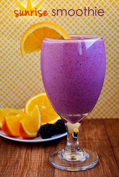 a purple smoothie with orange slices and blackberries