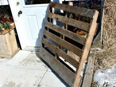 a wooden crate sitting on top of a sidewalk next to a white door and snow covered ground