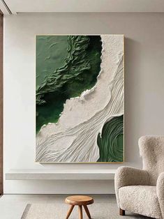 an abstract painting hangs on the wall next to a chair and ottoman in a modern living room