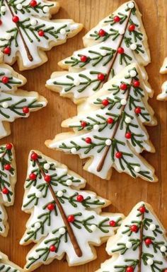 christmas cookies decorated with white icing and red berries are arranged on a wooden surface