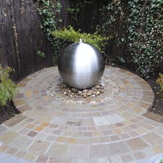 a large metal ball sitting on top of a brick patio