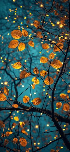 a tree with lots of yellow leaves on it's branches and lights in the background