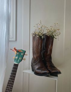 a ukulele and cowboy boots are sitting on a shelf next to a door