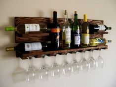 wine glasses and bottles are lined up on a wooden shelf above the wine glass holders