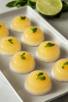 small desserts are arranged on a white plate with lime wedges in the background