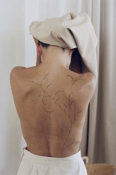 a woman with a hat on her head has a flower tattoo on her back