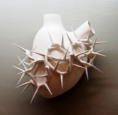 a white vase with spikes sticking out of it's sides on a table top