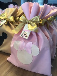 three bags with minnie mouse ears on them, one pink and one yellow are sitting on a table