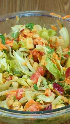 a glass bowl filled with salad on top of a wooden table