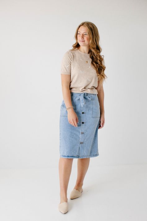 Create an instant feminine look wearing the 'Cassidy' Skirt! Featuring a button-front design and tie waist, this denim midi skirt makes a perfect choice for both casual or formal occasions. The soft, lightweight denim in a regular fit offers comfort, while the pull-on style allows easy wear. Pair the 'Cassidy' with a black tee and sneakers for a fun day in the city or running errands in town! 75% Cotton 25% Polyester Hand Wash Cold Do Not Bleach Hang to Dry Low Iron if Needed Model Height 5'7" | How To Wear A Skirt Plus Size, Angela Braniff Mom Uniform, Pentecostal Fall Outfits, How To Style Jean Skirt, Casual Denim Skirt Outfit, Amish Fashion, Modest Mom Outfits, Modest Athletic Wear, Modest Skirt Outfits