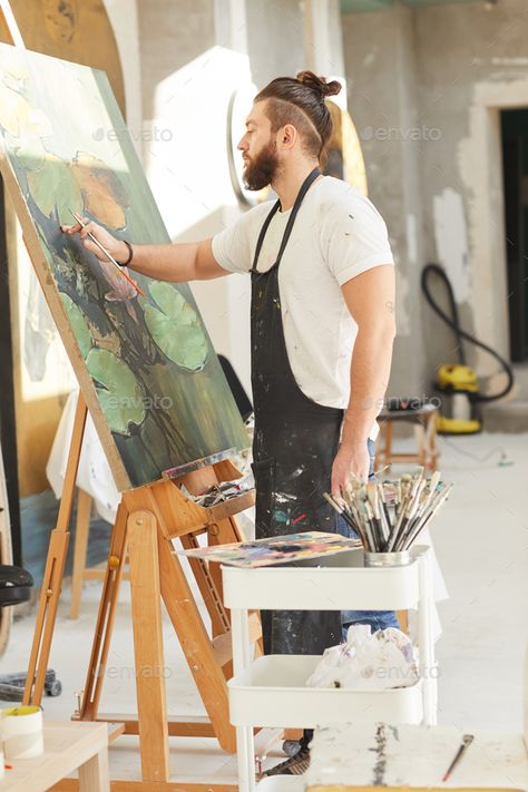 Bearded Male Artist Painting on Easel in Workshop by seventyfourimages. Vertical full length portrait of contemporary bearded artist painting picture on easel while working in art studio li... #Sponsored #seventyfourimages, #Workshop, #Vertical, #length Artist At Work Photography, Male Painter Photography, Painter Photography Artists, Male Artist Aesthetic, Pictures Of Artists, Workshop Aesthetic, Painting On Easel, Artist Vibes, Side View Portrait