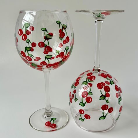 Sip your favorite red or white wine in style with these beautiful cherry wine glasses. The sleek, minimalist design complements any table setting, making it an ideal choice for everyday use or special gatherings. Surprise the wine enthusiast in your life with this thoughtful and practical gift. The wine glasses are double painted with high quality glass enamel paint and then heat cured for durability.  Highlights: Set of 2 wine glasses Handcrafted with care Vibrant cherry red color Minimalist an Cherry Glass Painting, Cherry Wine Glass Painting, Summer Wine Glass Painting Ideas, Cute Wine Glass Designs, Wine Glass Acrylic Painting, Paint And Sip Wine Glasses, Painting Cocktail Glasses, Painting Ideas On Wine Glasses, Paint Wine Glasses Ideas