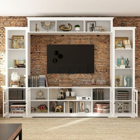 This wall unit features a 68 /102inch console, two pier units and an overhead bridge providing ample storage options. This 68/102 inch unit features gunmetal finished knobs, glass doors with wood framing, open storage, adjustable shelving. Tops and ends are solid planked panels, oversized thick tops and parting rails. (68"NOT INCLUDE 2 Side Cabinet) Features Four piece unit consists of two piers (left and right), a 66.5 console and 68.1" bridge Maximum Recommended TV Size: 65" Made of MDF, Tempered Glass Overall Dimensions: 102" W x 14.6" D x 78.2" H/68"W x 14.6"D Finish: White Size: 102"-WITH SIDECABINET - White. Dark Wood Tv Stand, Tv Shelf Ideas, Tv Shelf Design, Black Living Room Set, Tv Cabinet Wall Design, White Living Room Set, Grey Living Room Sets, Tv Nook, Tv Storage Unit