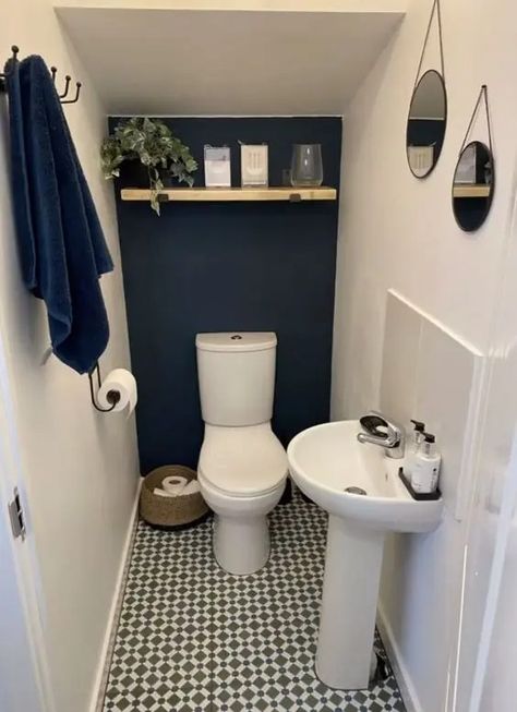 a small and cool under the stairs powder room with a navy accent wall, a printed floor, an open shelf with decor and a free standing sink looks stylish Understairs Toilet, Vogue Decor, Wc Decoration, Wc Ideas, Tiny Powder Room, Cloakroom Toilet, Small Downstairs Toilet, Bathroom Under Stairs, Bathroom Redecorating