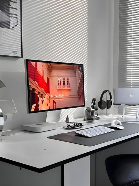 Modern and minimalist workspace featuring a large monitor displaying artistic content, a monochrome theme with black and white colors, and sunlight filtering through blinds. The desk is equipped with a Mac mini, wireless keyboard, and various tech accessories neatly arranged, complementing a stylish and functional setup Minimalist Pc Setup, Minimalist Desks, Minimal Workspace, Aesthetic Home Office, Monochromatic Aesthetic, Positive Environment, Desk Setups, Computer Desk Setup, Minimalist Desk