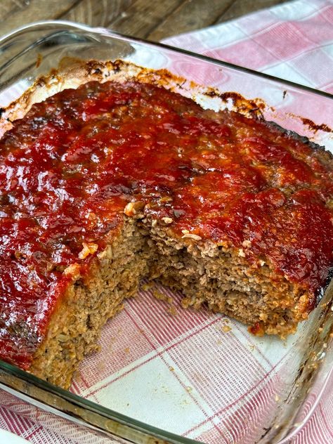 A mostly pan full of ketchup and brown sugar glazed meatloaf showing a moist, meaty filling with oats baked in a glass baking dish. Hamburg, Meatloaf In A Pan, Meatloaf In Cake Pan, Award Winning Meatloaf Recipes, Dolly Parton Meatloaf, Simple Meatloaf Recipes Easy Bread Crumbs, 3lb Meatloaf Recipe, Pork Beef Meatloaf, Amish Hamburger Casserole