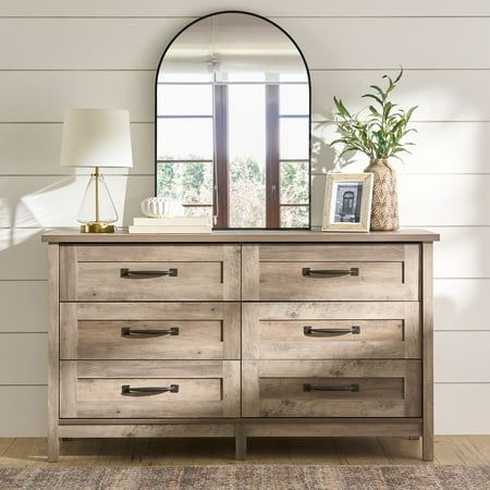 Create a rustic-inspired look while adding versatile storage options to your bedroom with this dresser from the Better Homes & Gardens Modern Farmhouse collection. This beautiful chest of drawers features six easy gliding drawers that open and close on smooth metal runners, making them ideal for convenient storage of an array of different items like stacks of button-up shirts and blue jeans to your collection of old t-shirts and sweat pants. It has room for all your stuff! Its spacious top surface provides you with additional space to store bedroom items and display your favorite home decor like an accent lamp, your makeup bag, bottles of perfume, and pictures of your family and friends. Its simple design and charming, good looks make this dresser a perfect fit for your bedroom. Finished i Dresser With Detached Mirror, Natural Wood Bedroom Dresser, Decorating Bedroom Dresser Top Ideas, Grey And Brass Bedroom, Guest Bedroom Farmhouse Style, Farmhouse Style Master Bed, Industrial Farmhouse Dresser, Tan Headboard Bedroom Color Schemes, Extra Large Dresser Master Bedrooms