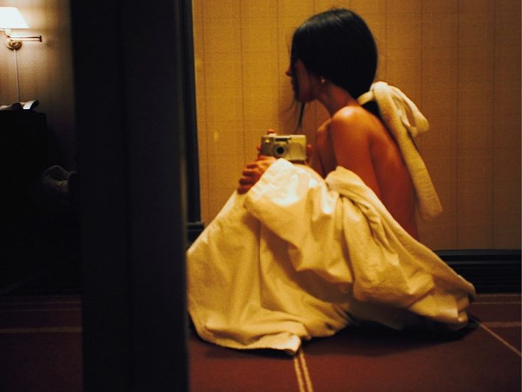 a woman sitting on the floor taking a selfie with her camera in a bathroom