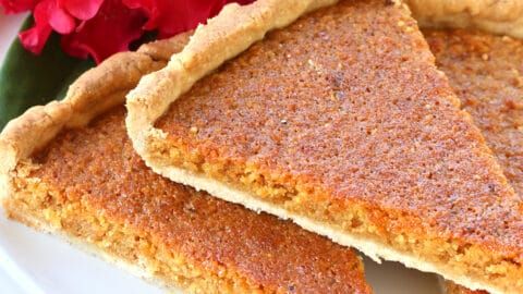 three pieces of pie sitting on top of a white plate next to a red flower