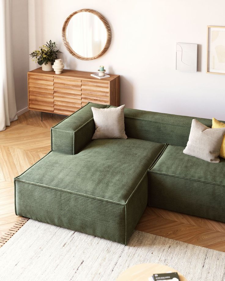 a green couch sitting on top of a hard wood floor next to a white rug