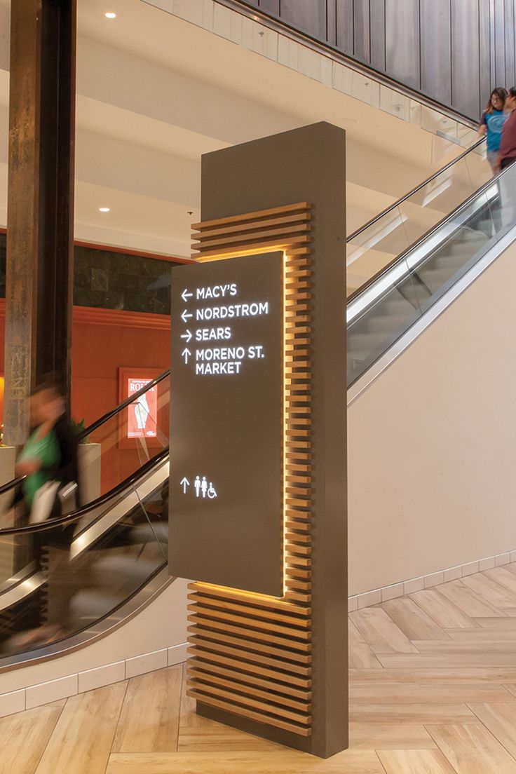 an escalator in a building with people walking up and down the stairs next to it