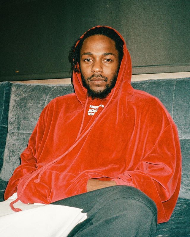 a man in a red hoodie sitting on a couch