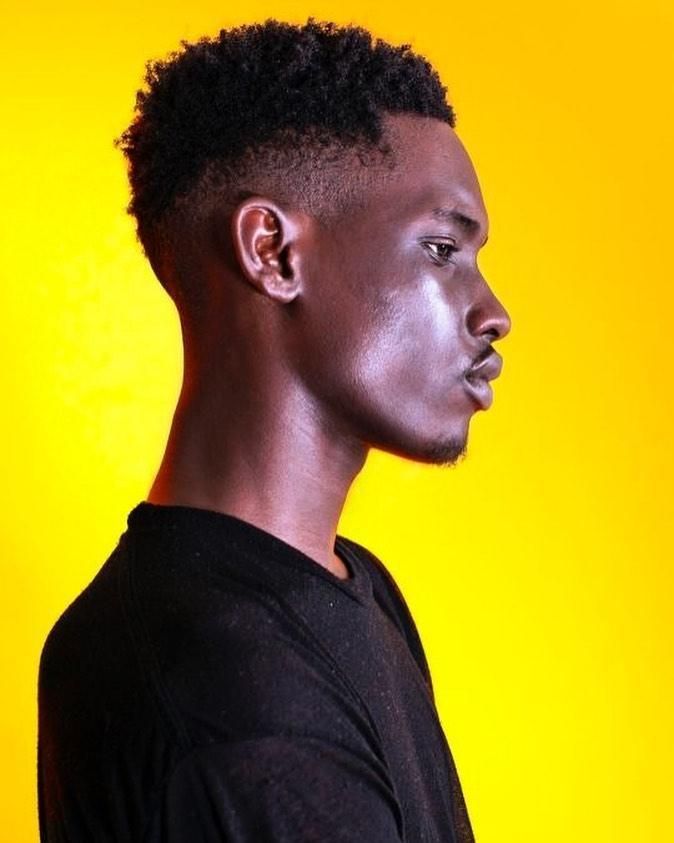 a man with black paint on his face standing in front of a yellow background and looking off to the side