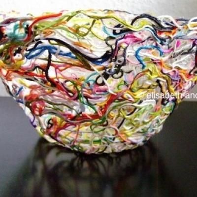 a glass bowl that is sitting on a black table with colorful paint splatters all over it