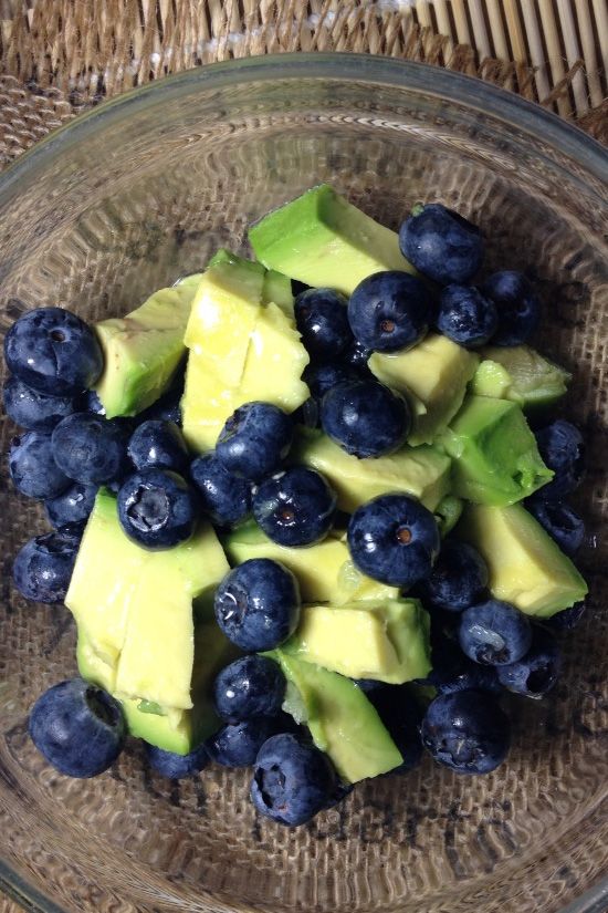 a glass bowl filled with blueberries and avocado