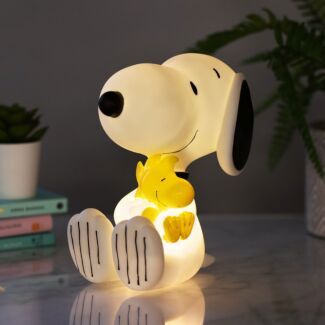 a snoopy lamp sitting on top of a table next to a potted plant