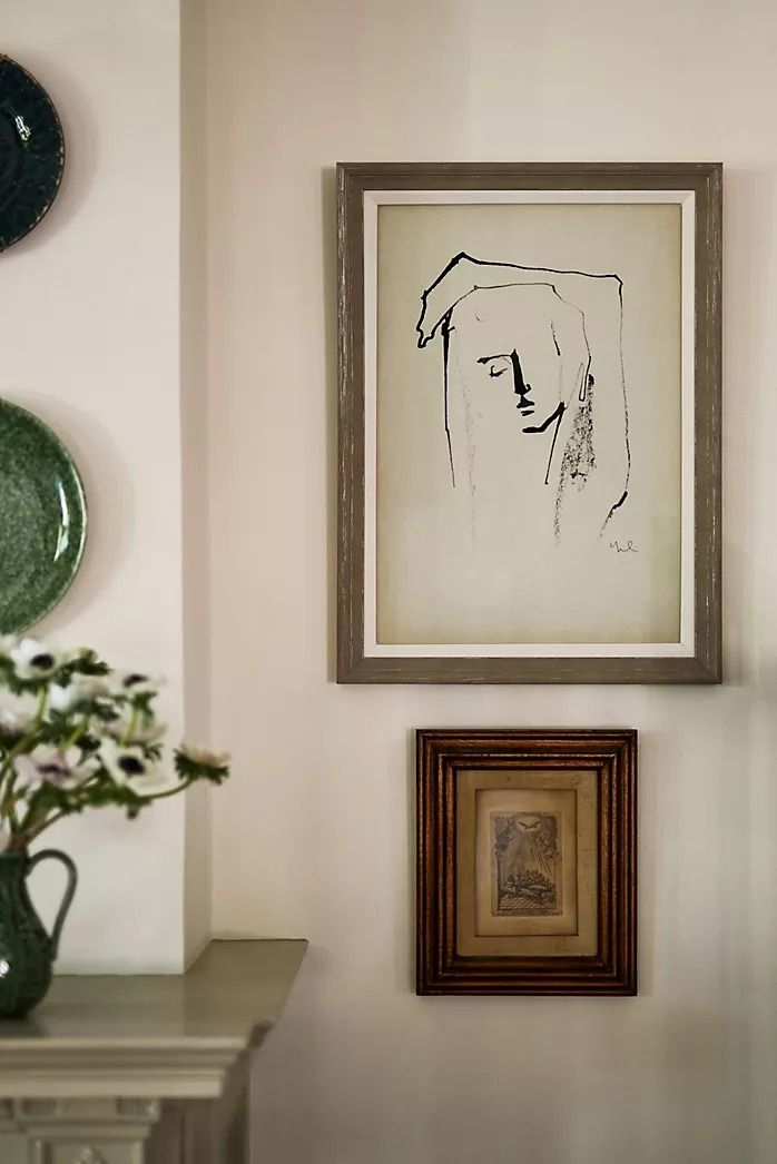 a painting hangs on the wall next to a vase with flowers