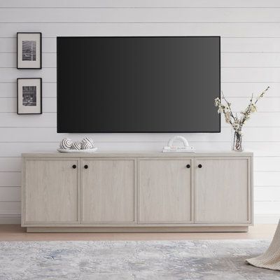 a large flat screen tv mounted to the side of a wooden cabinet in a living room