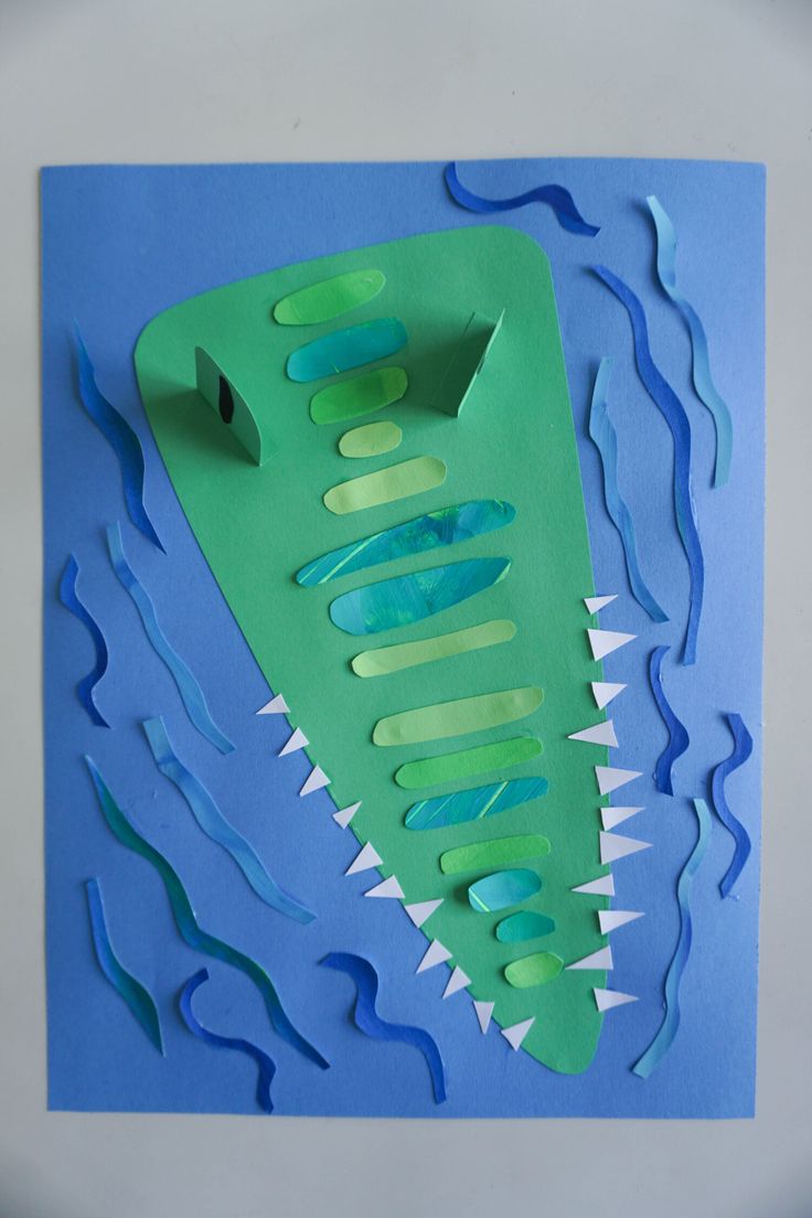 a paper cut out of a green boat floating on top of the ocean with blue water