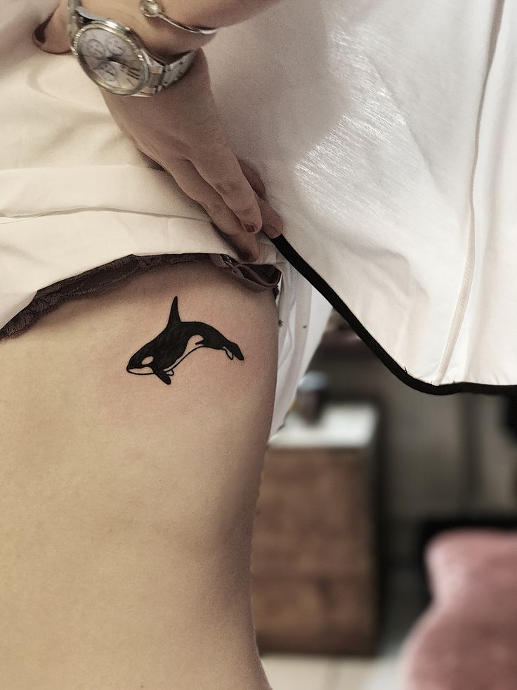 a woman with a tattoo on her stomach is holding a knife to the side of her thigh