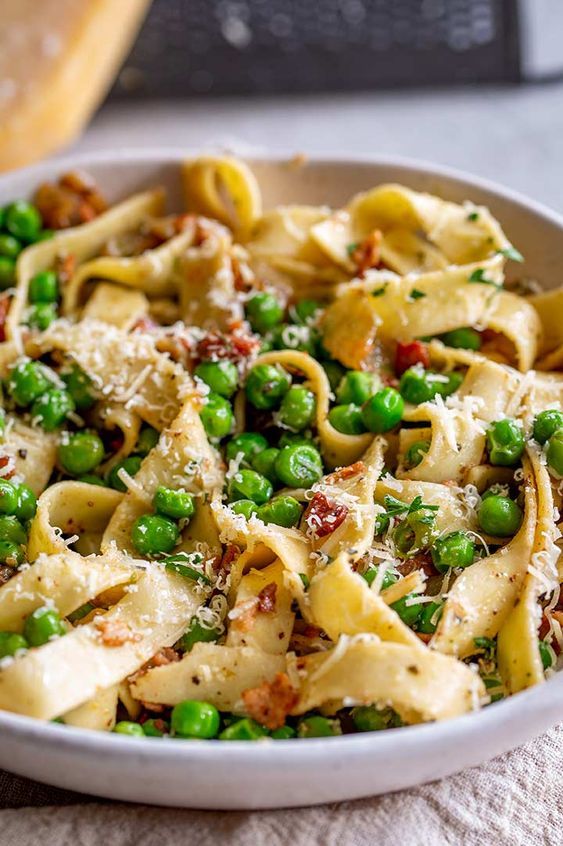 a white bowl filled with pasta and peas