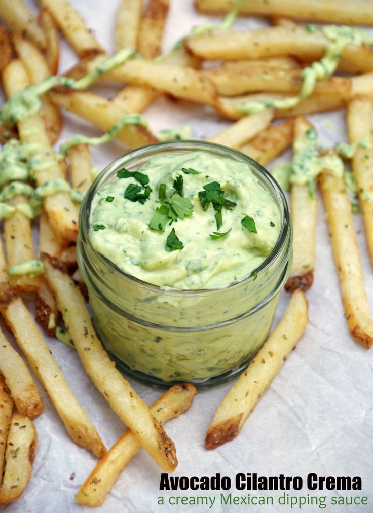 avocado and cilantro cream in a small glass jar surrounded by french fries