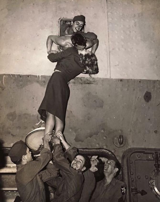 an old black and white photo of people in the air with one woman on her back