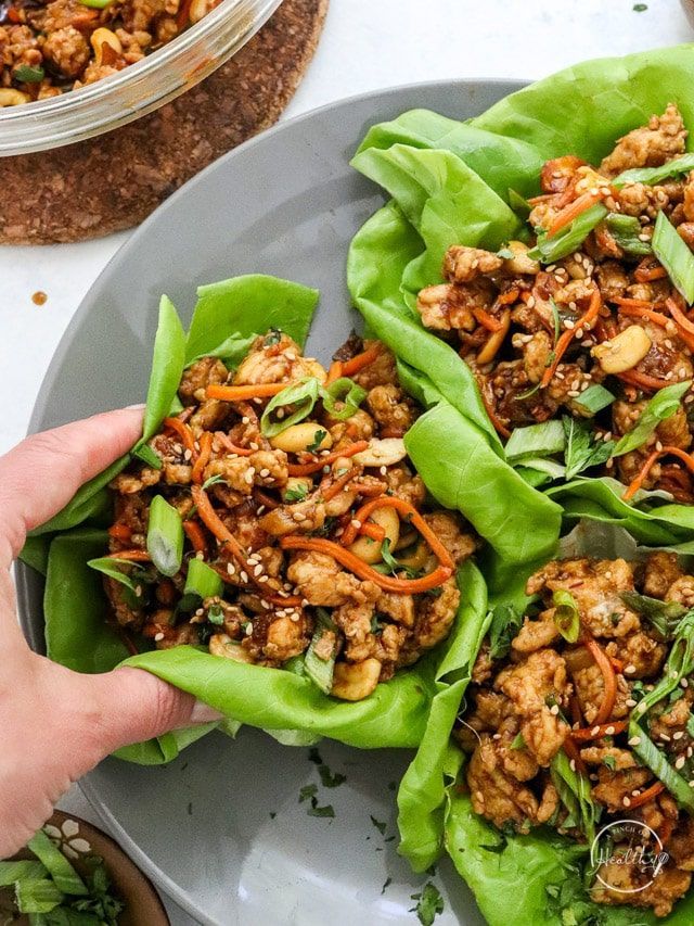 someone is holding up some lettuce wraps with meat and vegetables in them on a plate