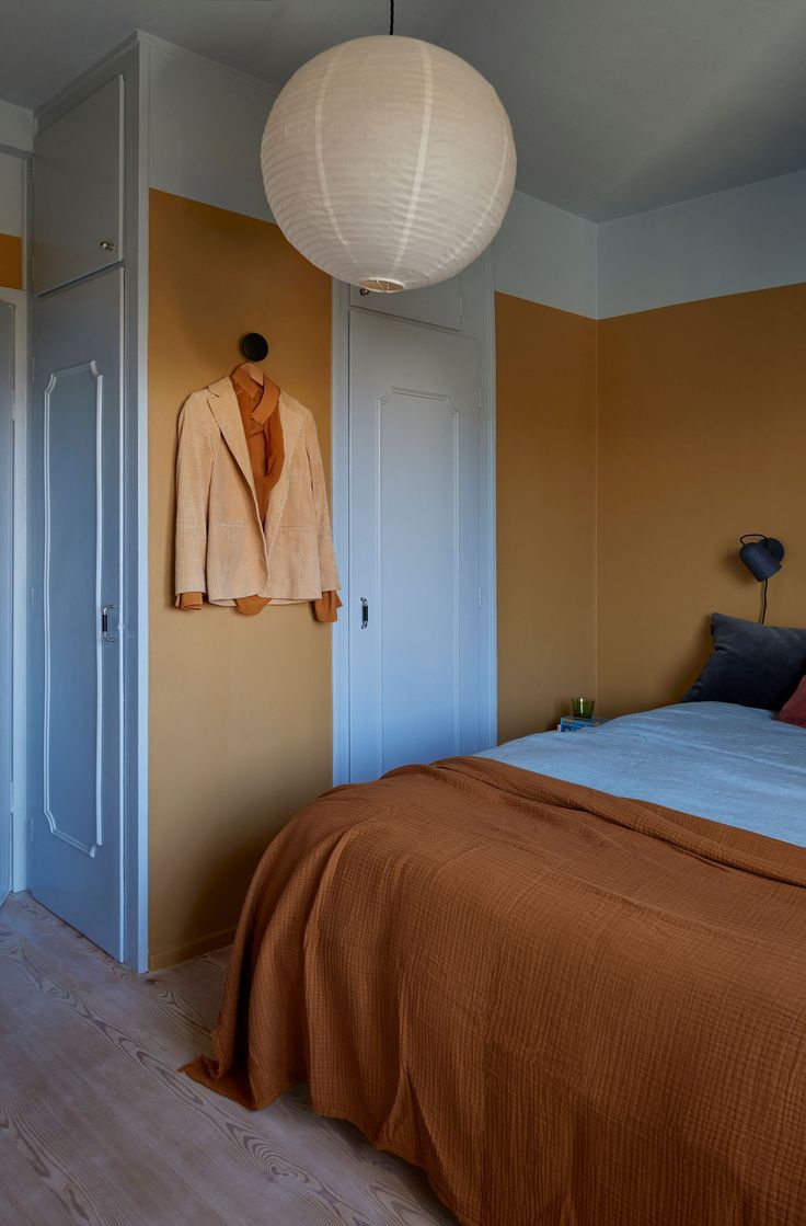 a bed room with a neatly made bed and a hanging jacket on the wall above it