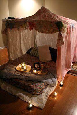 a bed that has candles on it in the middle of a room with a canopy over it